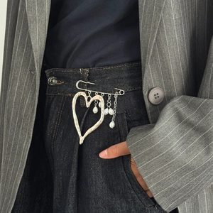 Detail shot of heart-shaped silver lava brooch with pearls pinned on pinstripe blazer