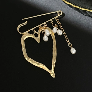 Detailed view of golden heart safety pin brooch with dangling irregular pearls