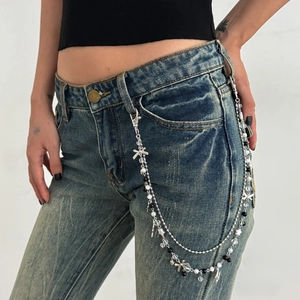 Silver punk star chain with pearls and butterfly charm on blue denim jeans