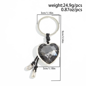 Detail view of heart-shaped grey crystal keychain with silver droplets and braided rope