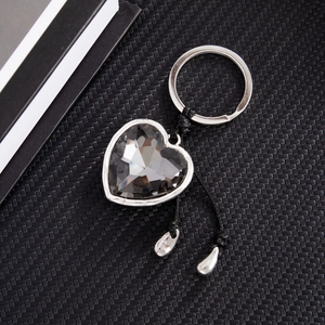 Detail of faceted grey heart crystal keychain with silver frame and woven black rope