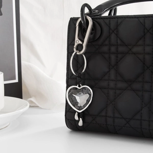 Detail of heart crystal keychain with silver frame on black quilted leather handbag