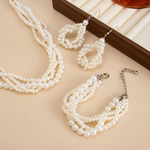 Close-up of multi-layer pearl necklace, bracelet and teardrop earrings set with silver clasps