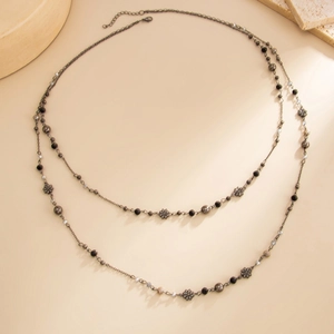 Detail of vintage bohemian double-layer necklace featuring silver flowers and beads
