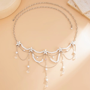 Detail of layered silver waist chain featuring crystal flowers and pearl drops on beige background