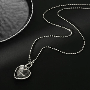 Vue détaillée d'un collier en billes argentées avec pendentif en cristal taillé en cœur