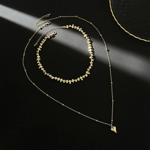 Collier multi-rangs doré avec pendentif cœur et perles métalliques sur fond sombre