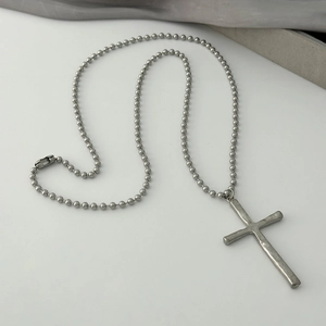 Silver vintage textured cross pendant necklace with metallic ball chain on clean background