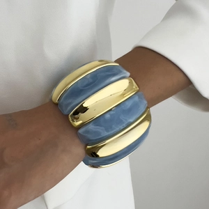Detailed shot of bold wide bangle featuring gold metal links and blue marble resin blocks