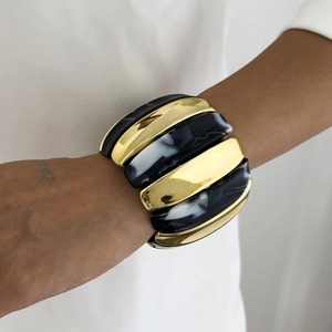 Detail of wide stretch bracelet with gold metal and black marble resin segments