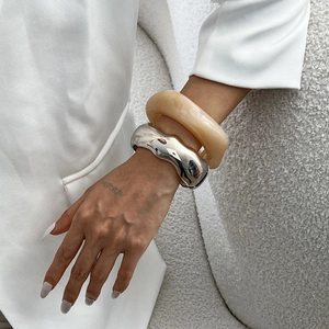 Chunky silver wave metal bracelet and amber resin bangle set on model's wrist
