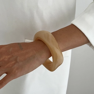 Close-up of translucent amber resin bangle with a thick geometric minimalist design