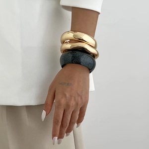 Irregular chunky gold and black resin bangles stack for women on a model