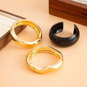 Detailed view of stacked gold and glittery black bracelets on a wooden jewelry display