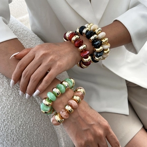 Bracelets en résine de couleurs variées avec détails dorés portés par un mannequin