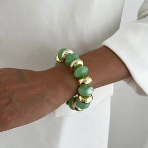 Détail de perles en marbre vert et sphères dorées sur un bracelet perlé minimaliste