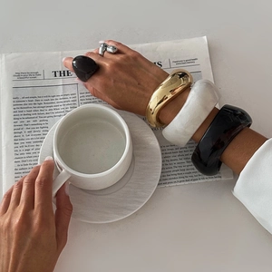 Fashion chunky resin bangles and silver rings styled with a coffee cup for a chic look