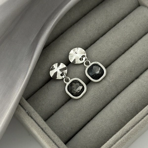 Detail of square dark grey crystal drop earrings with textured metal studs and velvet finish
