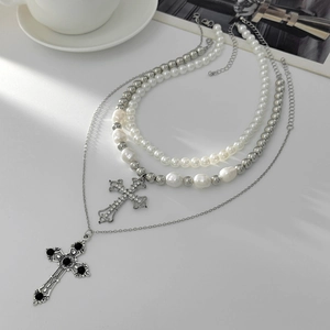Detail view of multi-layered pearl necklace with crystal cross and black gemstone pendants