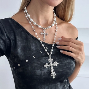 Layered pearl necklace set with crystal cross pendants shown on a black dress