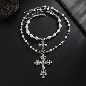 Detail of layered silver necklaces with ornate cross pendants and white pearls
