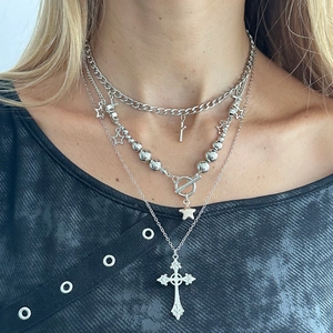 Close-up of layered silver cross and star pendants with vintage T-bar clasp design