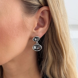 Close-up of model wearing silver tiered earrings with faceted grey square stones
