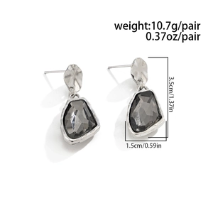 Detail view of geometric drop earrings featuring grey faceted stones and silver frames