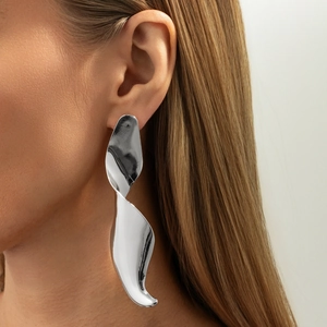 Close-up of oversized silver abstract spiral earrings with polished mirror finish on model