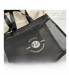 Detailed macro view of black mesh tote bag with circular white logo and fabric handles