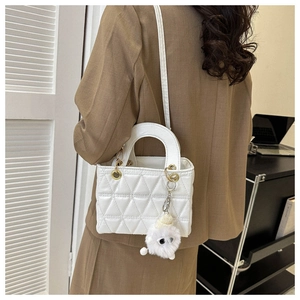 Side view of white quilted PU leather crossbody bag with cute plush monster pendant charm