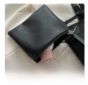 Close-up of black leather mini neck pouch with pink cosmetic item showing interior space