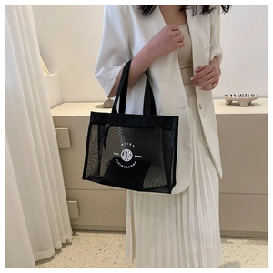 Detail of black mesh tote bag with a white round logo and a removable inner pouch