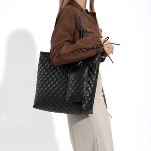 Grand sac cabas noir matelassé avec pochette assortie porté par un mannequin