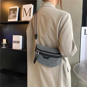 Sparkly rhinestone crossbody sling bag with woven strap shown on a model in a modern room