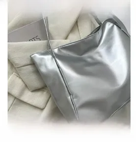 Detail view of silver metallic tote bag with glossy texture and slim shoulder straps