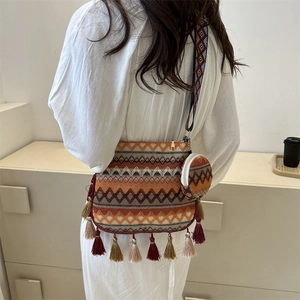 Sac bandoulière bohème tissé avec motifs géométriques et glands porté par un modèle