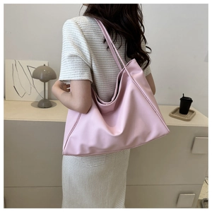 Vue latérale d'un grand sac cabas rose pâle porté par un mannequin dans un décor épuré
