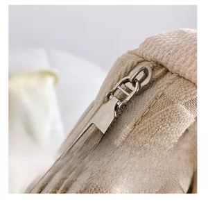 Close-up of smooth silver zipper on a beige checkered canvas tote with woven texture