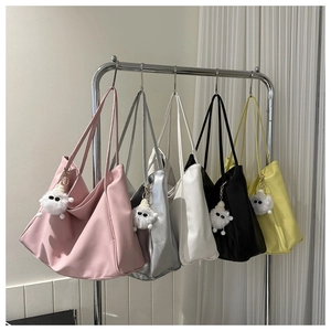 Detail view of large tote bags in five colors with cute plush monster charm accessories