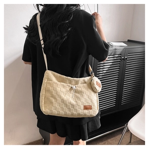 Detail of beige quilted shoulder bag featuring adjustable drawstring and mini coin purse