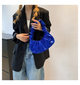 Detailed view of royal blue pleated cloud bag worn as a shoulder bag on a black blazer