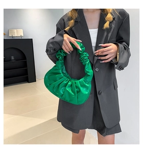 Detail of bright green crescent scrunchie bag with ruched leather texture on a model