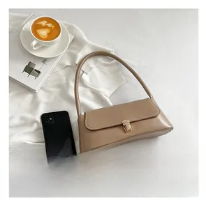 Detail view of khaki baguette bag with golden metal buckle next to a smartphone