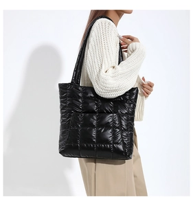 Detail view of black quilted tote bag with square pattern and glossy nylon texture