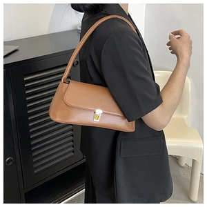 Detail view of brown leather underarm bag featuring a golden metal twist lock buckle