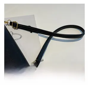 Detalle de correa ajustable con herrajes dorados en bolso negro con diseño de cocodrilo