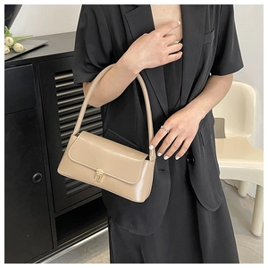 Fashionable beige faux leather baguette bag with gold metal buckle on a black blazer