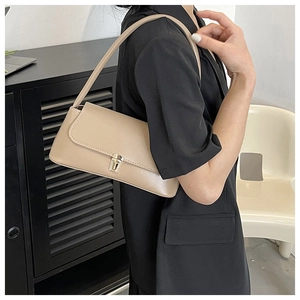 Close-up of minimalist beige baguette bag with a golden buckle worn by a model