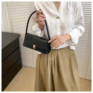 Detail of a vintage black baguette bag with gold metal clasp on a female model